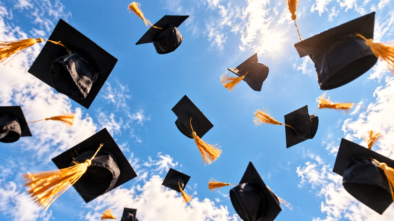 Graduation caps flying into a blue sky